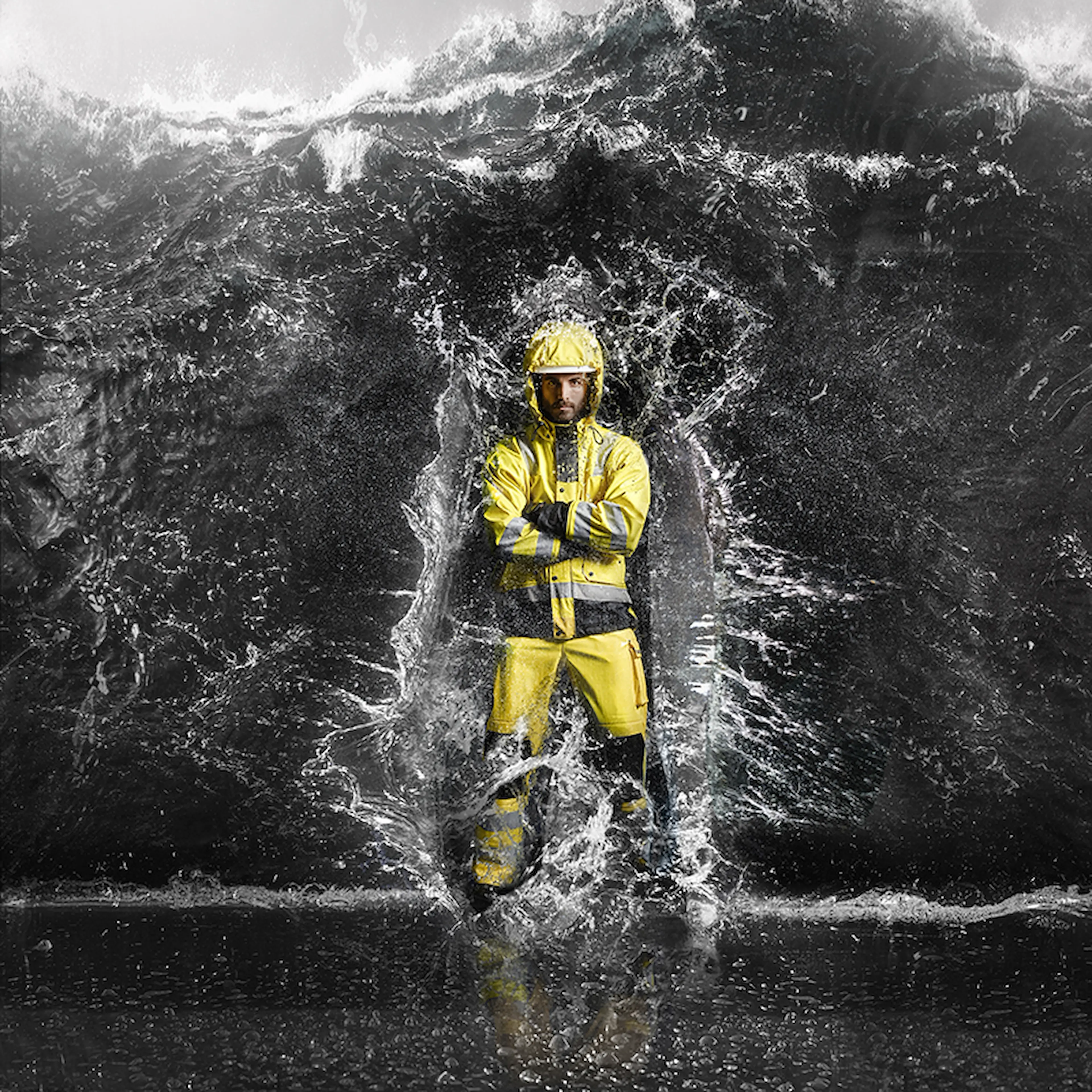 Worker in high-visibility rainwear standing firm as powerful waves crash around the body—engineered to withstand extreme weather, heavy rain and the toughest working conditions.